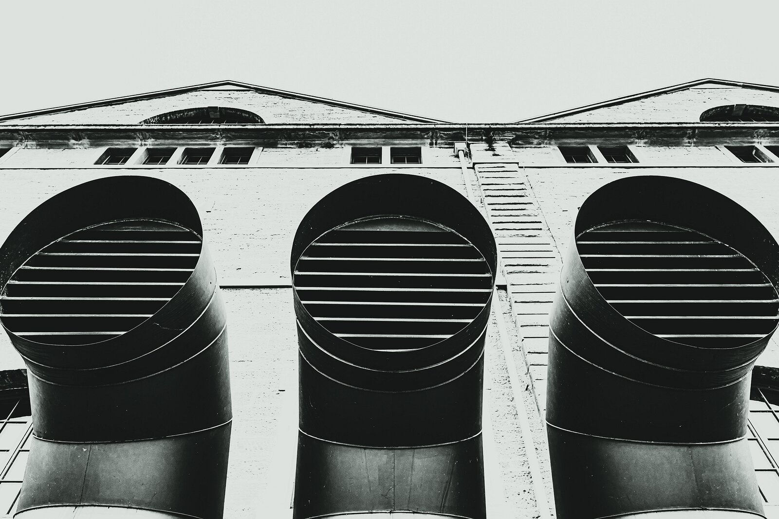 Bold Ducts Upward view of three large round ventilation ducts on a white industrial building.