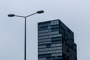 Monochrome Mood Streetlight frames a tall grid-patterned glass tower against an overcast urban sky.