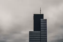 Moody Highrise Dark modern skyscraper with rooftop antenna silhouetted against an overcast sky.
