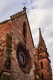 Medieval Craft Red sandstone church façade with ornate rose window and soaring Gothic spire.