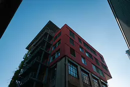 Rising Lines A modern red and brick building with balconies rises against a clear blue sky.