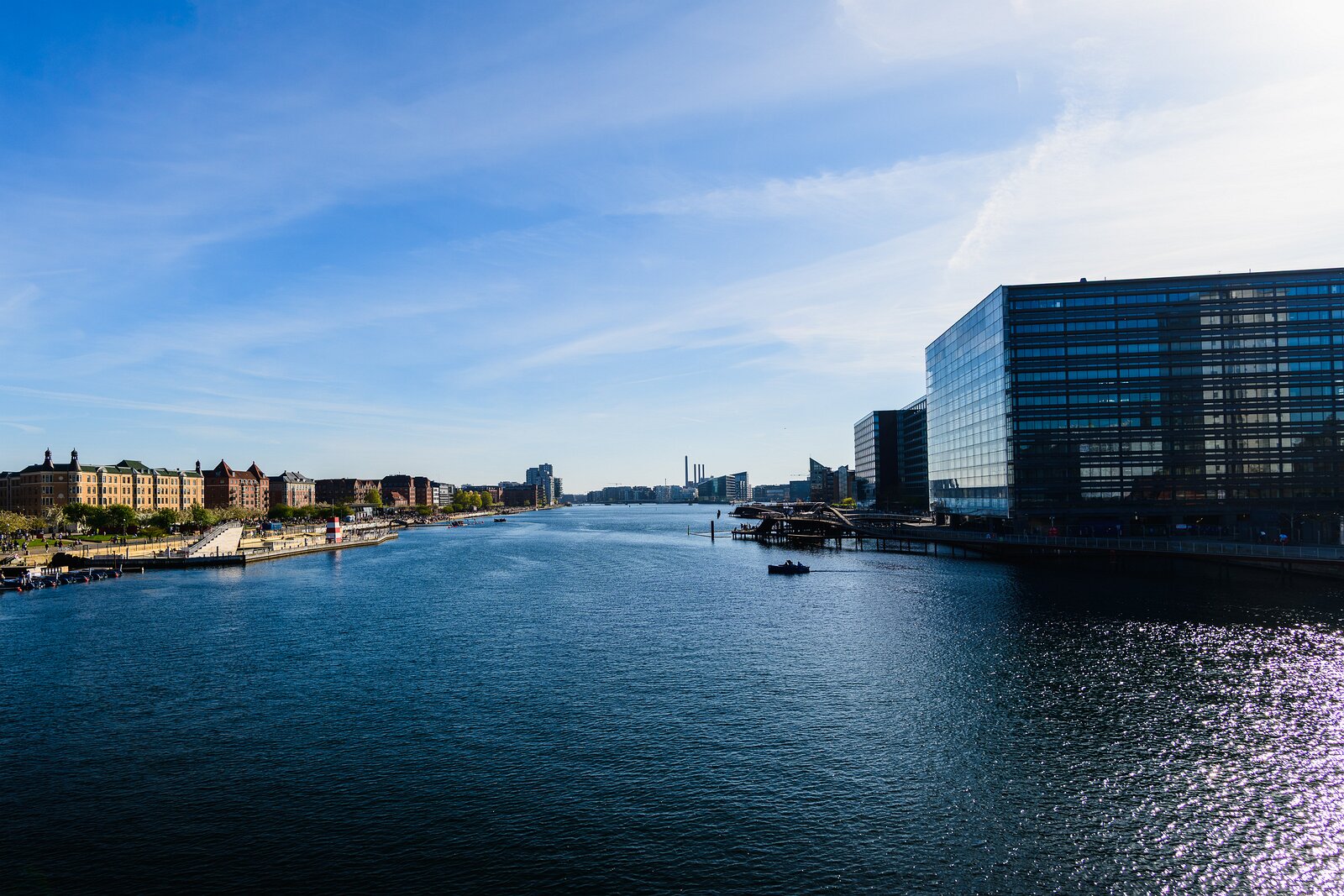 Waterfront Lines Kalvebod Brygge canal with modern glass offices and historic brick blocks lining water in Copenhagen.