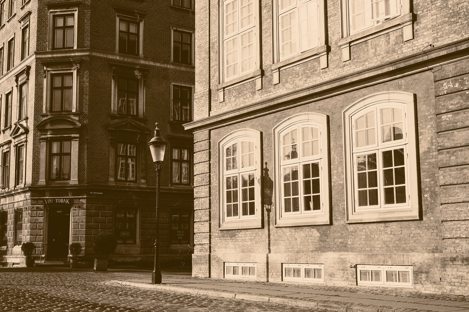 Vintage Streetscape Sepia street scene on Ny Vestergade with a vintage lamp casting shadow against brick facades in Copenhagen.