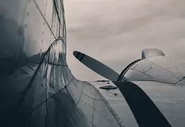 Riveted Grace A close-up shows the curved body and rivets of a vintage propeller plane.