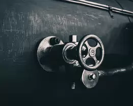 Iron Throttle Metal valve wheel mounted on the side of a steam-locomotive boiler.