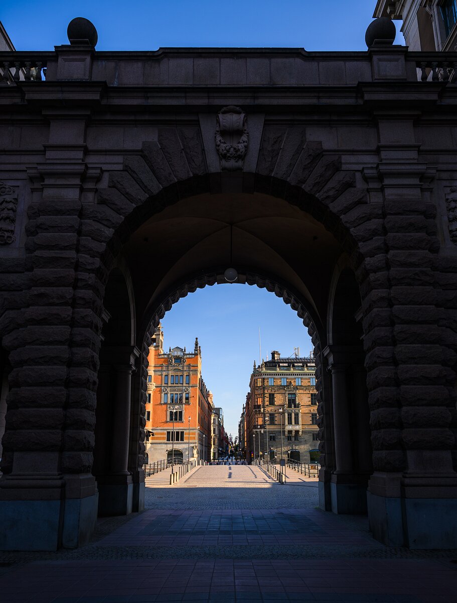 Stone Gateway The granite arch of Sweden’s Parliament (Riksdagshuset) frames a sunlit city street beyond.