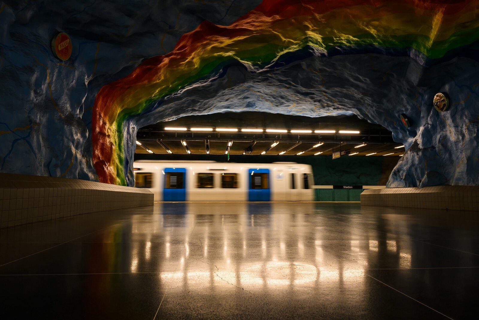 Color Cavern A blur of a passing train slides beneath the rainbow-painted cave ceiling of Stockholm’s Stadion metro station.