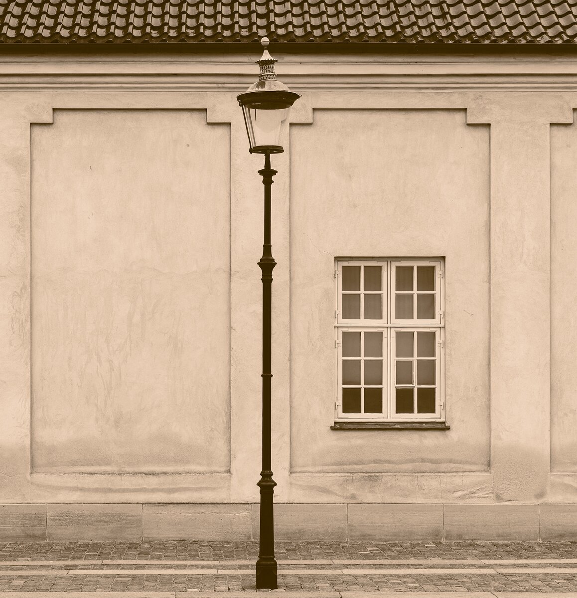Quiet Street Central vintage streetlamp before plaster wall and window in Copenhagen.