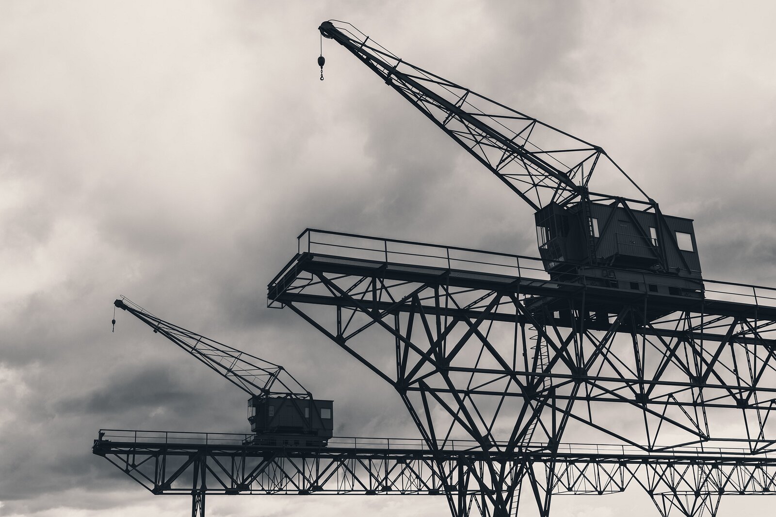 Industrial Giants Two lattice steel harbor cranes silhouetted against cloudy sky in Copenhagen.