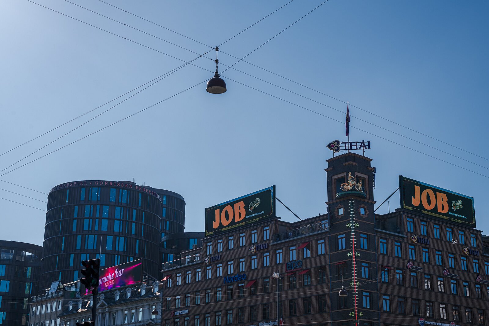 Urban Junction JOB billboard and thermometer tower on Rådhuspladsen beneath crossing twires, Copenhagen.