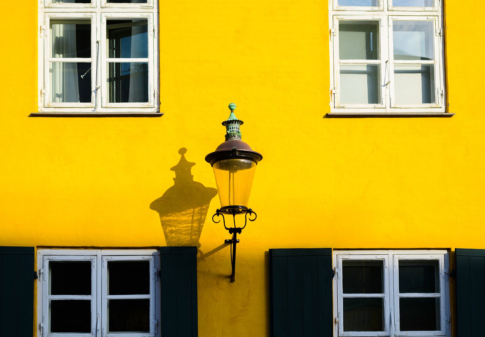 Historic Hue Lantern shadow on bright yellow Nyboder facade with white windows in Copenhagen.