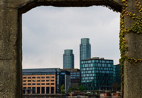 Concrete Window Twin cylindrical glass towers framed by weathered concrete arch on Copenhagen waterfront.