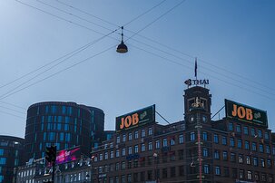 Urban Junction JOB billboard and thermometer tower on Rådhuspladsen beneath crossing twires, Copenhagen.