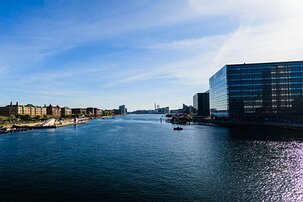 Waterfront Lines Kalvebod Brygge canal with modern glass offices and historic brick blocks lining water in Copenhagen.