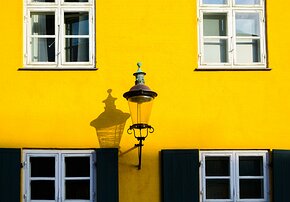 Historic Hue Lantern shadow on bright yellow Nyboder facade with white windows in Copenhagen.