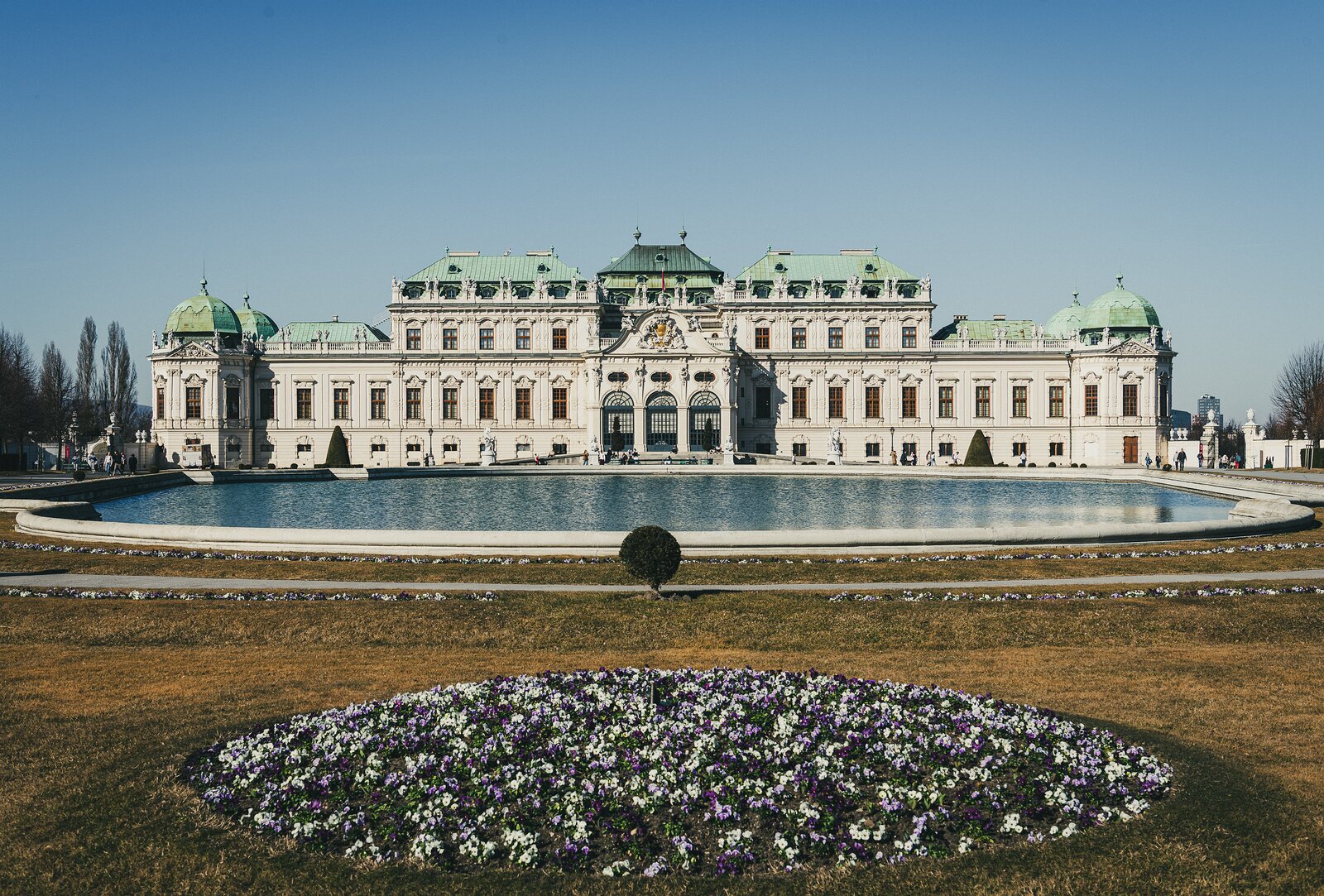 Baroque Grandeur Symmetrical façade of Vienna’s Upper Belvedere Palace reflected in its ornamental pool beyond spring flowerbeds.