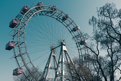 Nostalgic Carnival Upward view of the iconic Wiener Riesenrad Ferris wheel with red gondolas framed by bare tree branches.