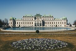 Baroque Grandeur Symmetrical façade of Vienna’s Upper Belvedere Palace reflected in its ornamental pool beyond spring flowerbeds.