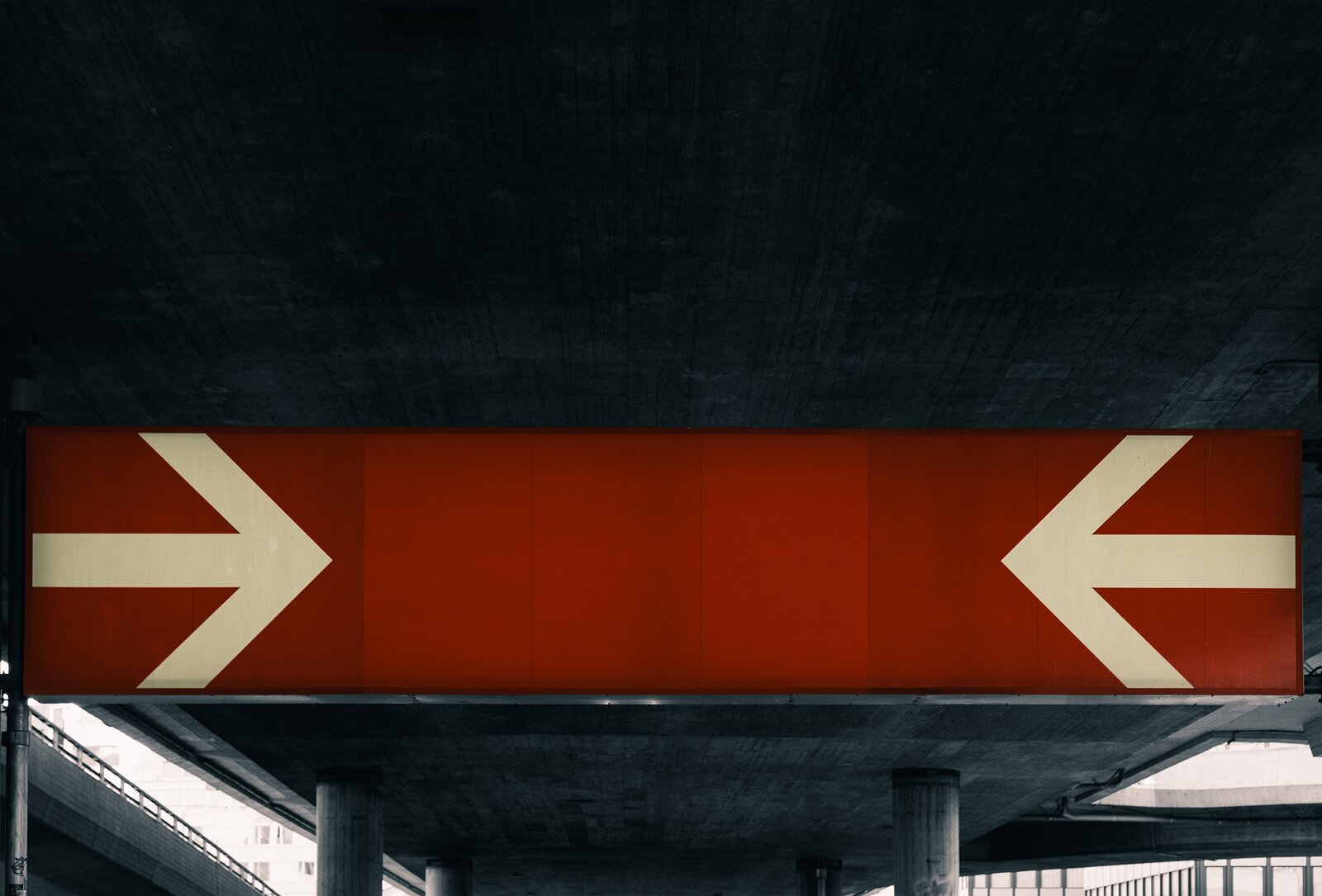 Both Ways Red overhead sign under a concrete overpass shows two large white arrows pointing toward each other, indicating left- and right-hand directions.