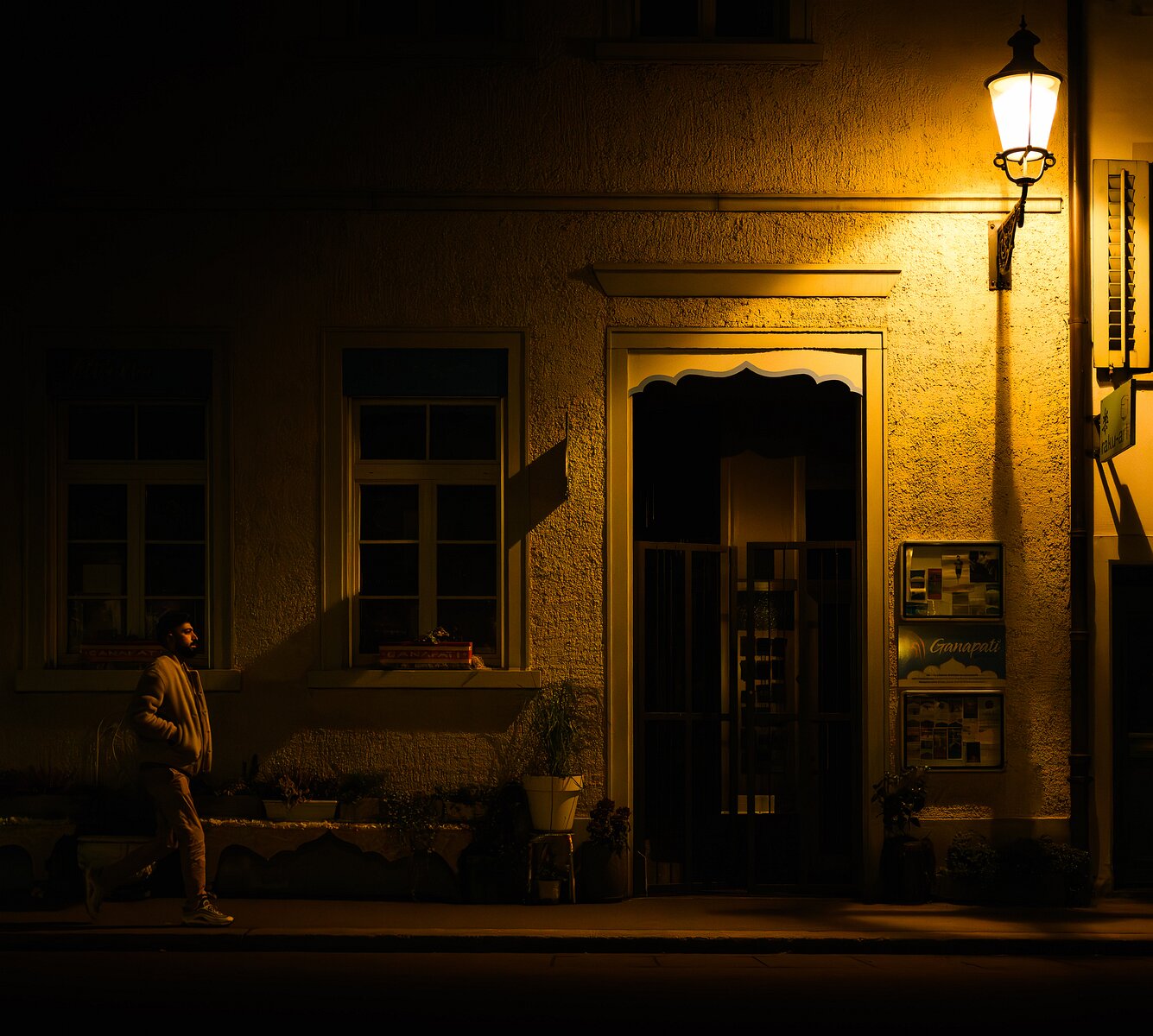Silent Street Man walks past a dimly lit building under a glowing streetlamp at night.